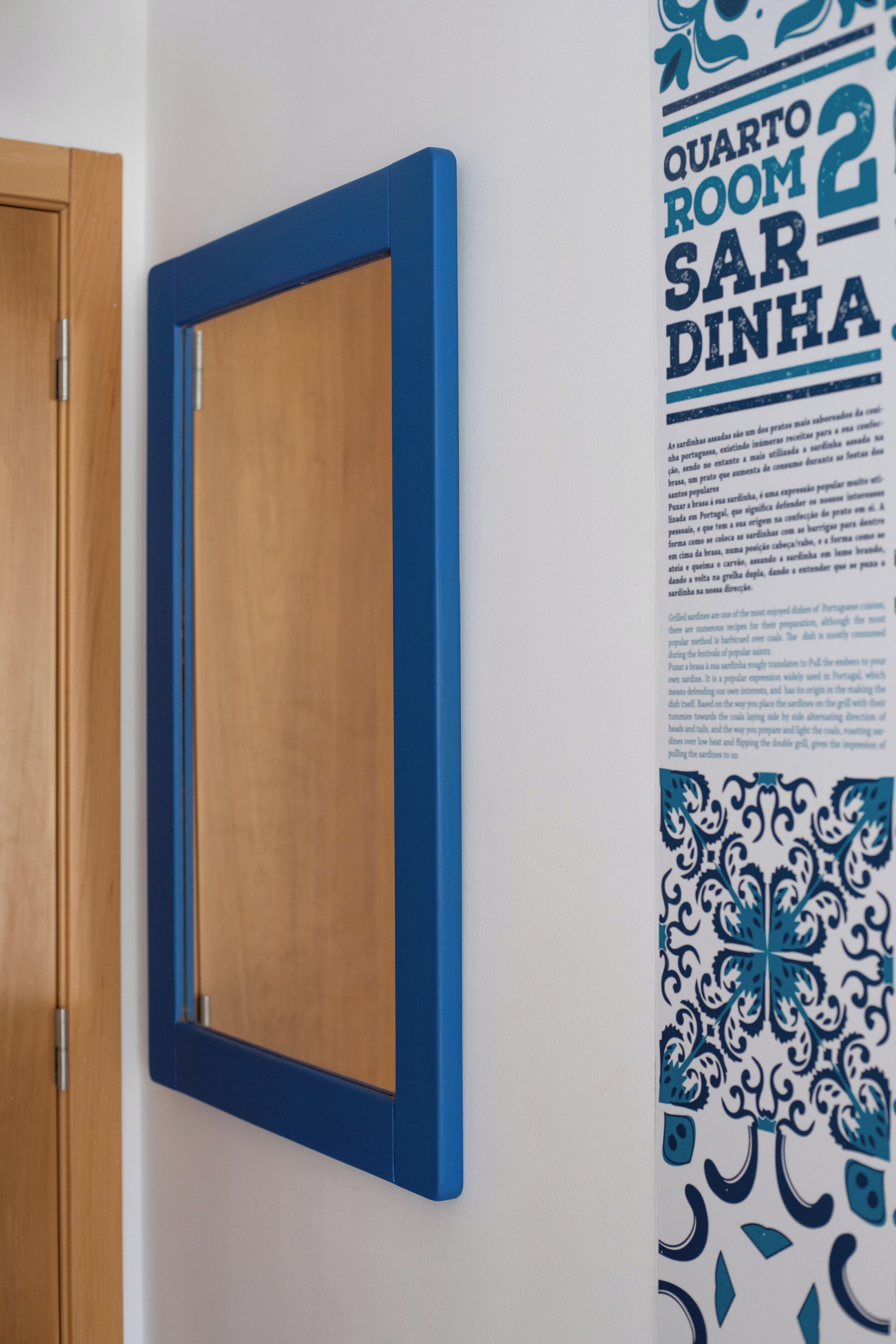 A room with a wooden door and a blue-framed picture on the wall.