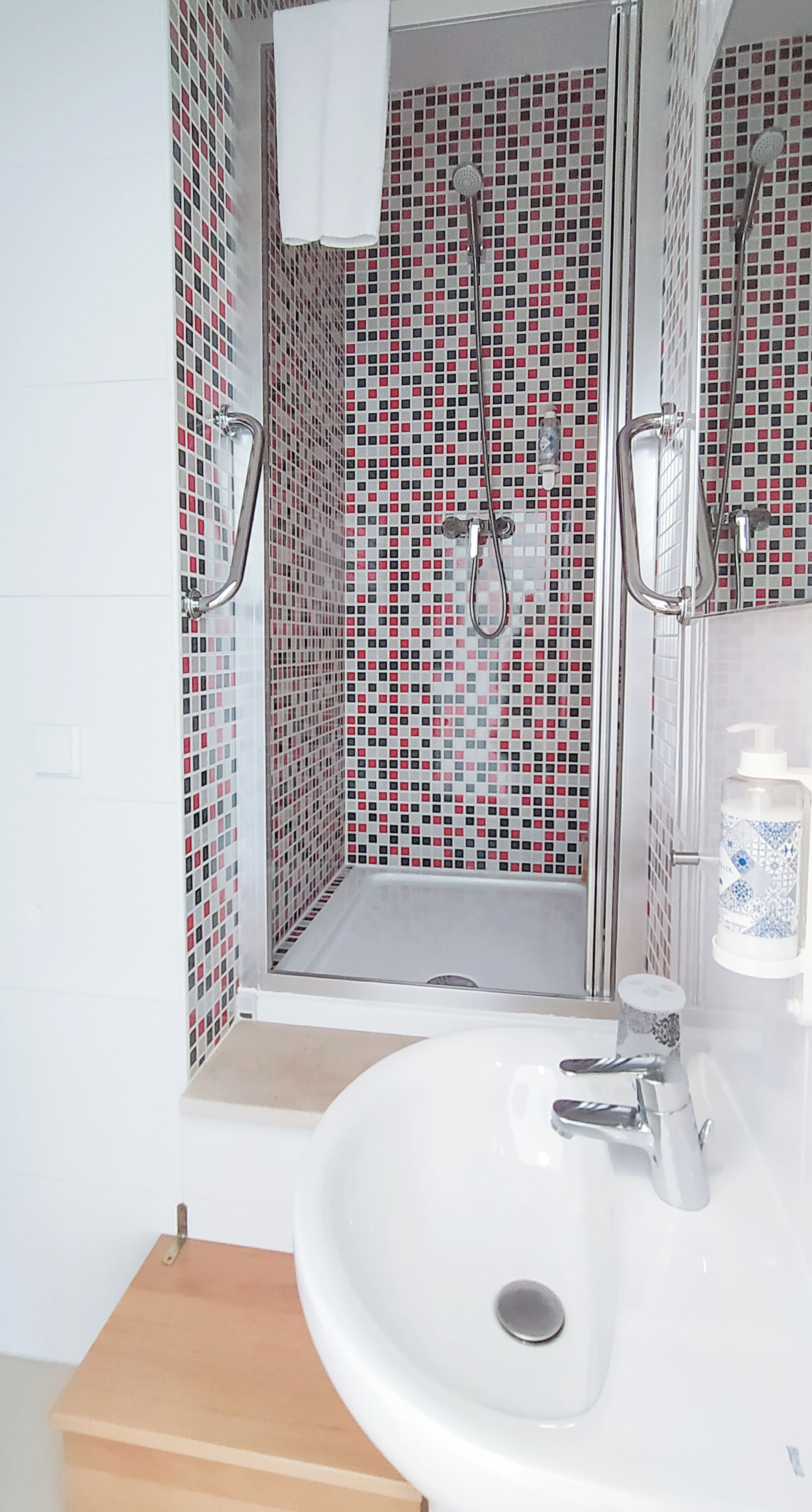 A bathroom with a shower, a sink, and a mirror.