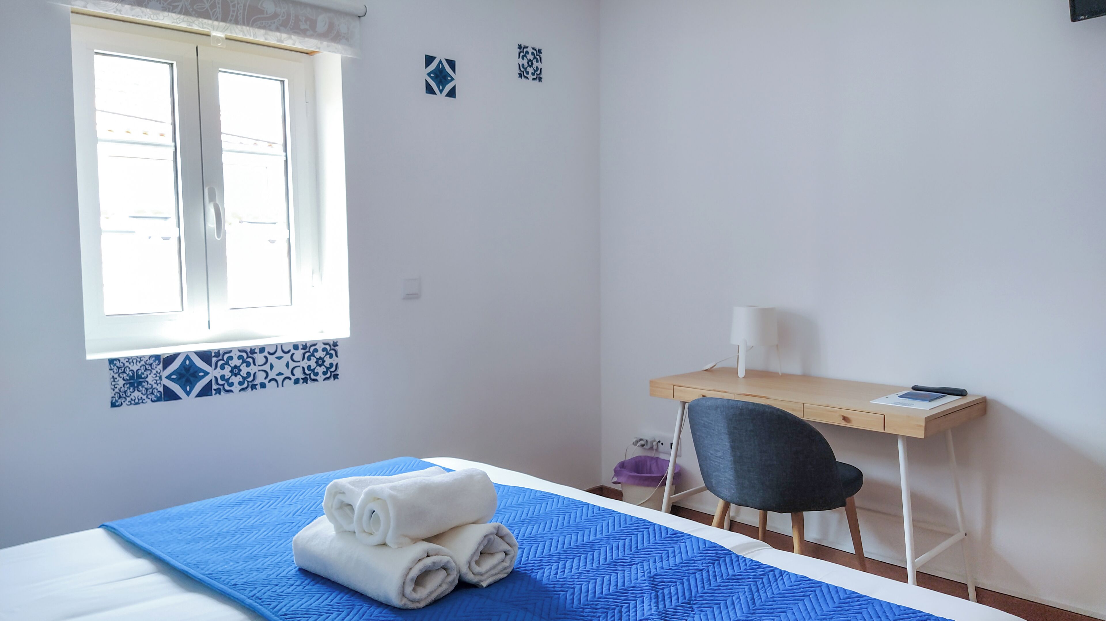 Un dormitorio con cama, escritorio, silla y ventana.