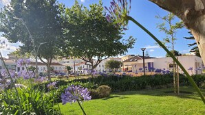 Un jardín con flores moradas y un edificio con un mural al fondo.