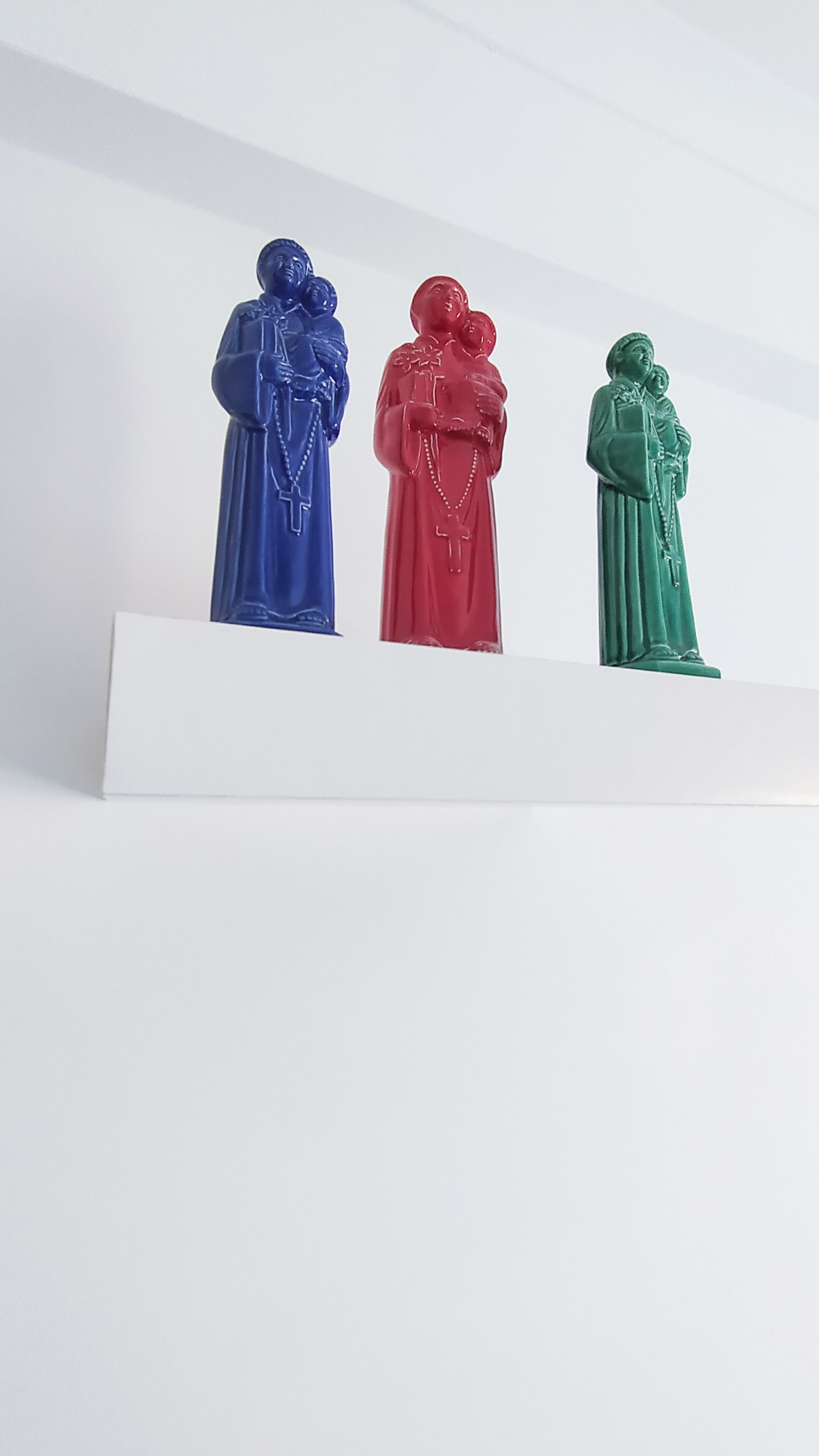 Tres estatuas sobre una repisa blanca.