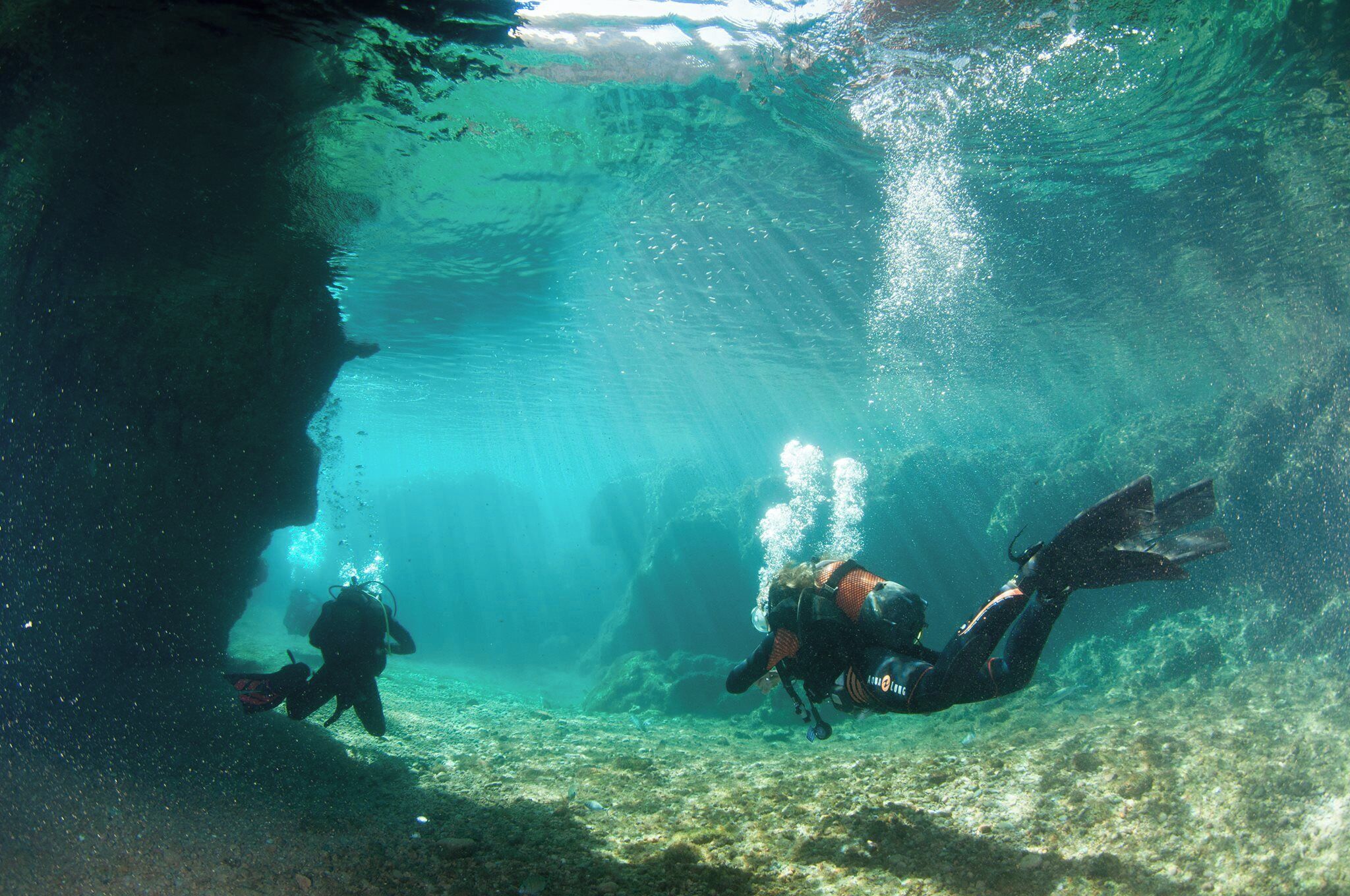 An underwater scene with divers exploring a submerged cave.