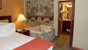A hotel room with a large bed, a bedside lamp, a stone wall, a bathtub, and a bathroom with a mirror and sink. - Rare 1BR for 4 at Westgate Park City. Ski-In/Ski-Out. Walk to Gondola. (Park City)