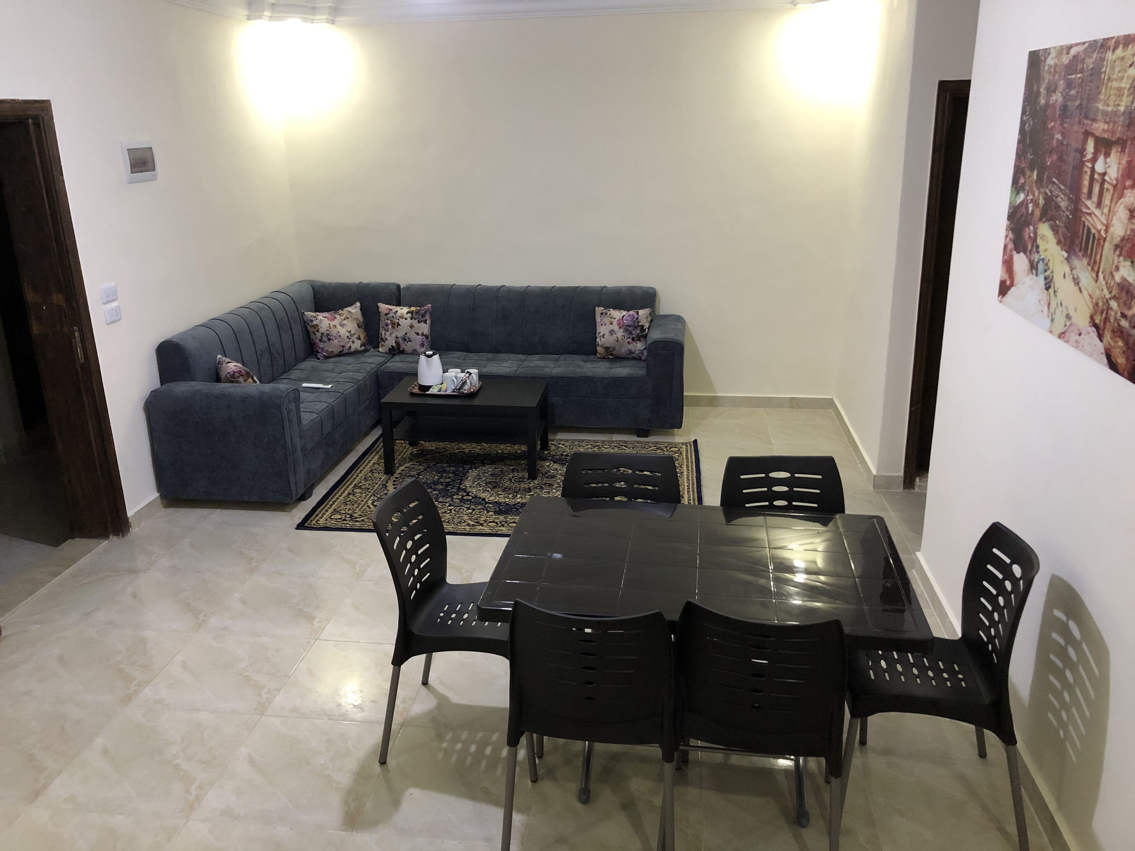 A living room with a dark blue sofa, a coffee table, and a dining table with chairs.