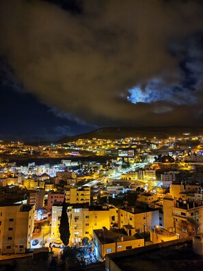 A nighttime cityscape with illuminated buildings and a cloudy sky. - Rakan Apartment (Wadi Musa)