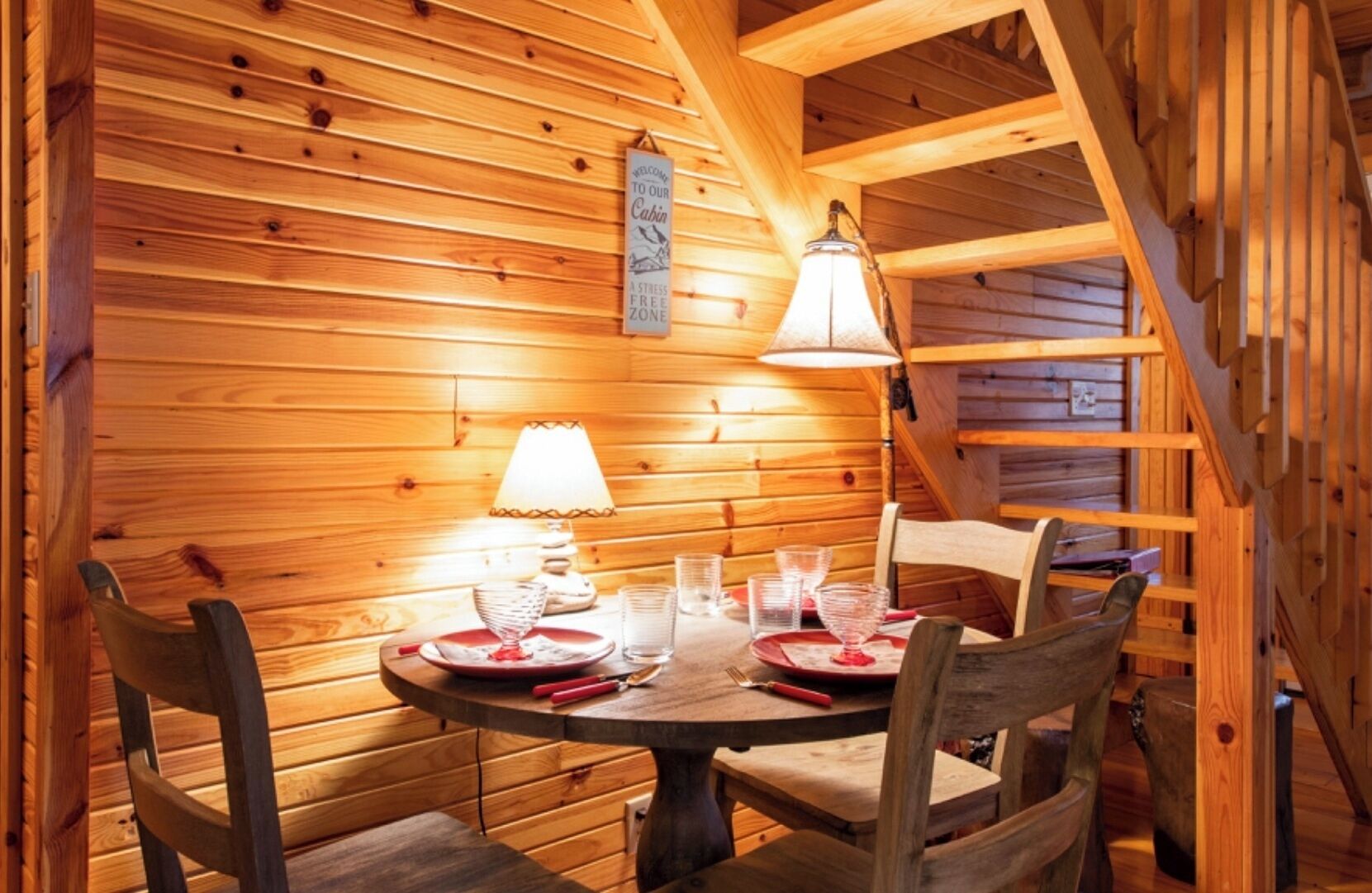 Ein Holzblockhaus-Interieur mit einem Esstisch für vier Personen, einer Lampe und einem Schild, das eine entspannte Zone kennzeichnet.