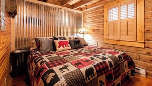 A cozy log cabin room with a bed, wooden walls, a ceiling fan, and a window with shutters. - Shaded Log Cabin Swim Spa 2 miles Lake Entrance & winery (Birdseye)