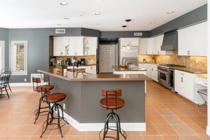Una cucina moderna con isola centrale, sgabelli da bar e un'ampia finestra.