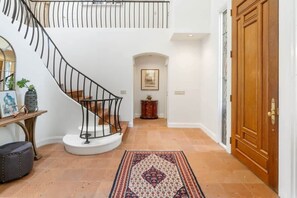 Una scala con ringhiera nera, una porta in legno e un tappeto decorato sul pavimento.