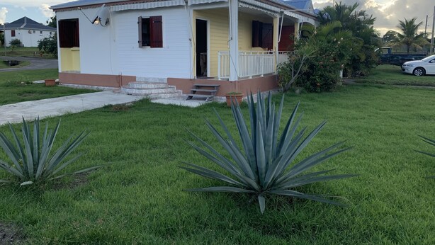 Una casa d'un pis amb una verament i un petit jardí davanter, i una camioneta aparcada a prop.