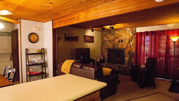 Una sala de estar acogedora con chimenea de piedra, un televisor y un comedor con mesa y sillas.