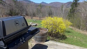 A barbecue grill with a deer logo, a wooden barrel, and a wooden deck. - Off Grid Mountain Farmhouse with amazing views, soaking tub, seclusion, internet (South Duxbury)