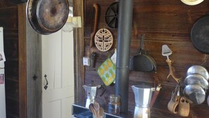 A kitchen with a white stove, hanging pots, a clock, and wooden walls. - Off Grid Mountain Farmhouse with amazing views, soaking tub, seclusion, internet (South Duxbury)
