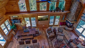 Un'ampia cabina con soffitto alto, pareti in legno e ampie finestre che si affacciano sulla foresta circostante.