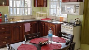 Una cocina con armarios de madera, estufa a gas, microondas y pileta.