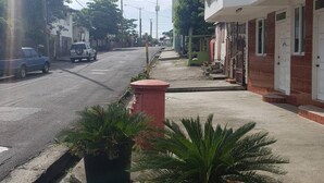 Una calle tranquila con edificios de dos pisos, una acera y automóviles estacionados.