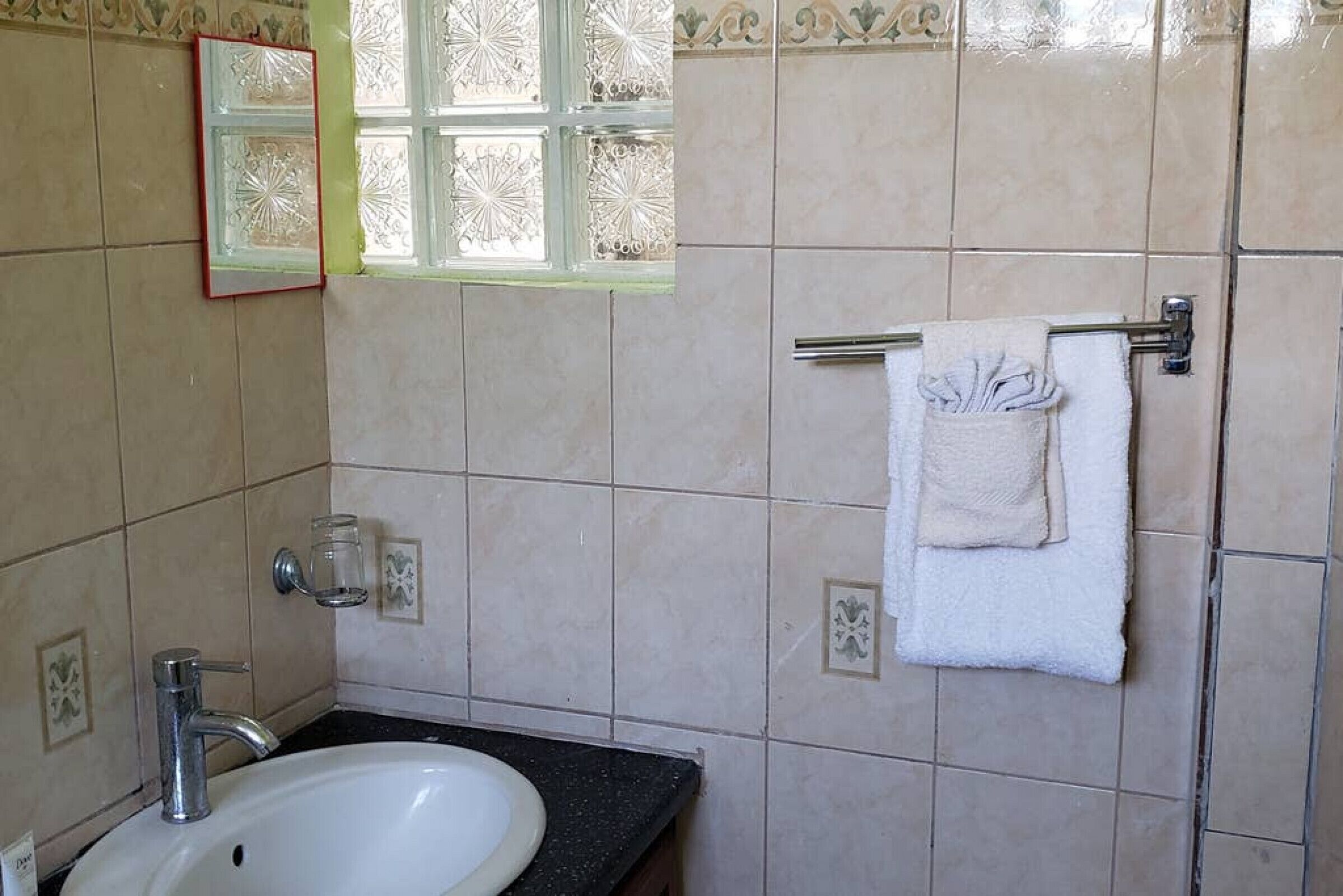 A bathroom with a sink, mirror, and towel rack.