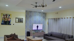 Un salon avec un canapé, une table basse, un téléviseur et un ventilateur de plafond.