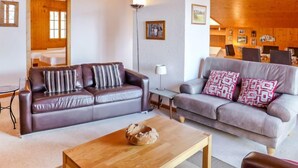Een moderne woonkamer met twee banken, een salontafel en een eethoek met stoelen.