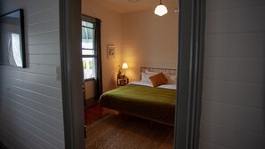 A bedroom with a bed, a nightstand, a lamp, and a window.