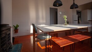 A modern dining area with a white table, black pendant lights, and a bench.