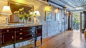 A room with a stone wall, wooden floor, a large mirror, and a wooden dresser with drawers. - Amazing Loft with Balcony Overlooking River Street by Lucky Savannah (Savannah)