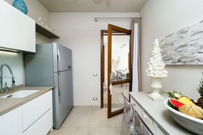 Kitchen features a stainless steel refrigerator, sink, and dining area with a table and chairs.