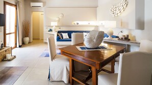 Ein modernes Wohnzimmer mit einem Holzesstisch, weißen Polsterstühlen, einem blauen Sofa und einer Wanddekoration.