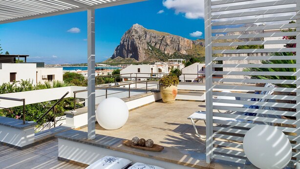 Eine Dachterrasse mit Blick auf einen Berg, weißen Geländern und Sitzgelegenheiten im Freien.