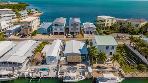 Vista aérea de um resort costeiro com vários edifícios, uma marina com barcos e uma visão clara do oceano.