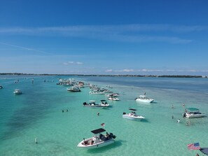 A marina with numerous boats docked in clear turquoise water, a clear sky, and a distant shoreline with buildings. - Geat Fishing & Ocean breeze, 40 ft dock for your boat with direct ocean access. (Tavernier)