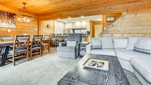 Ein gemütliches Blockhaus-Interieur mit Essbereich, einer Couch und einer Treppe, die zur Küche führt.