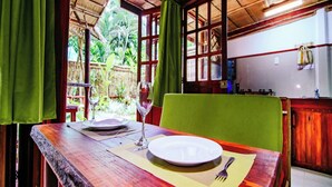 Un comedor con una mesa dispuesta para dos personas, una ventana con cortinas y vistas al exterior.