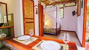 Una habitación con una cama, una mesa de comedor con platos y cubiertos, un espejo y un ventilador de techo.