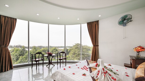 Habitación de hotel con una cama grande, una mesa con sillas y vistas al exterior.