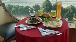 Una mesa con mantel rojo, dos platos de comida, un vaso de jugo y una botella de agua.