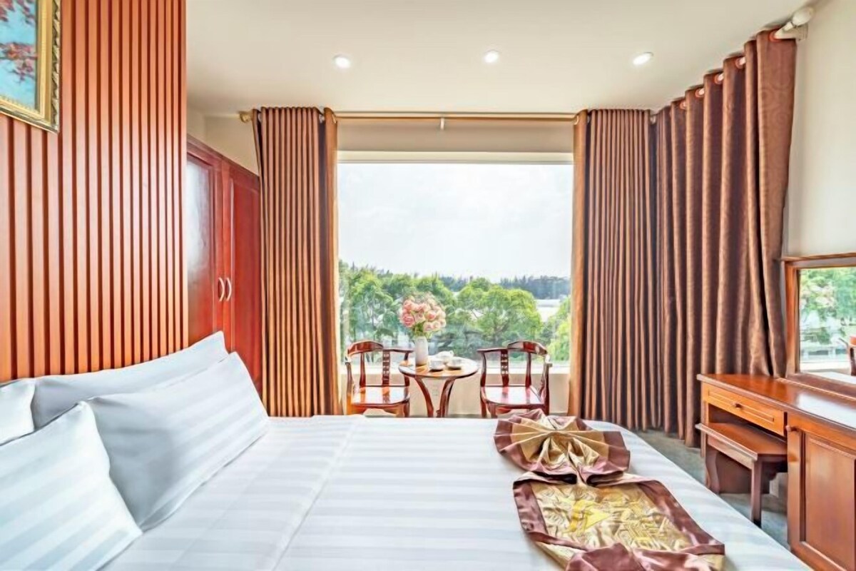 Habitación de hotel con una cama grande, un escritorio y vistas al exterior.