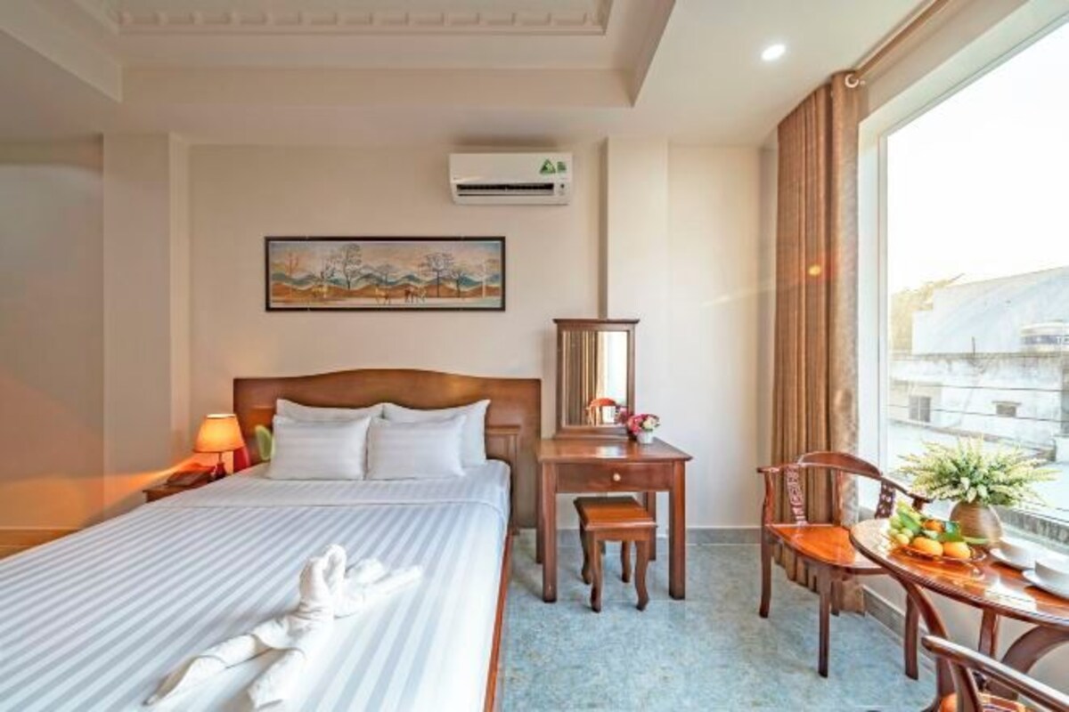 Habitación de hotel con cama, mesita de noche, silla y ventana con vistas.