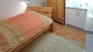 A bedroom with a wooden bed, a wardrobe, and a kitchenette.