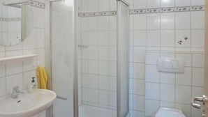 A bathroom with a shower, sink, toilet, and a mirror.