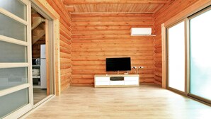 Une chambre de style rustique avec un plancher en bois, une armoire blanche, un téléviseur à écran plat et une porte-fenêtre coulissante sur le côté gauche.