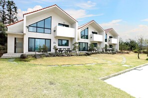 A modern two-story residential building with large windows and a tiled roof.