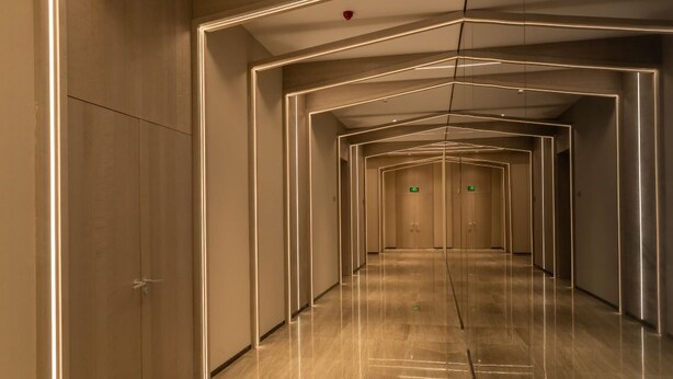 Un pasillo moderno de hotel con un diseño de iluminación geométrico en paredes y suelo.