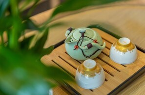 A tray with a green teapot and two white cups with gold designs. - Le Ville Residence (Xi'an)