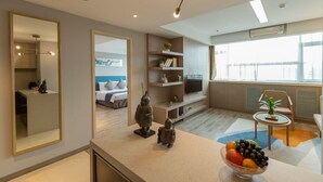 Una habitación de hotel moderna con cama, televisión, un pequeño comedor y un ventanal grande.