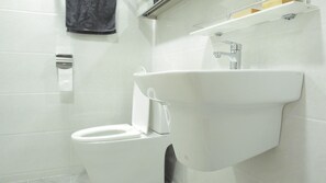 A bathroom with a white toilet, a wall-mounted sink, and a towel rack. - Dongdaemun PR. Mondern Studio (Seoul)