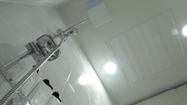 Un baño con ducha, toallero y secador de manos.