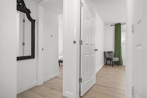Guest rooms lead to a cozy bedroom area with a large mirror and comfortable seating.