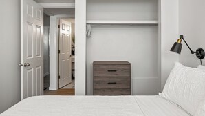 A bedroom with a bed, a dresser, a closet, and a desk lamp.