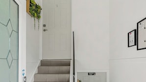 A staircase with a handrail, a door with a number sign, and a wall-mounted plant.